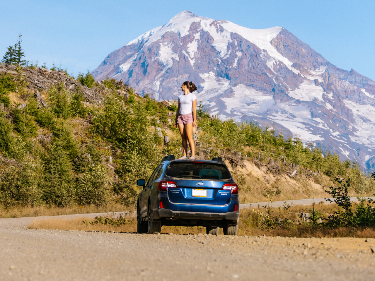 Woman standing on Subaru Outback looking at mountains