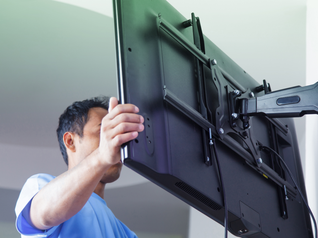 A person mounting a TV to the wall