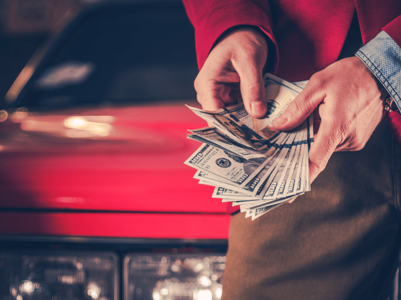 Person holding money in front of car